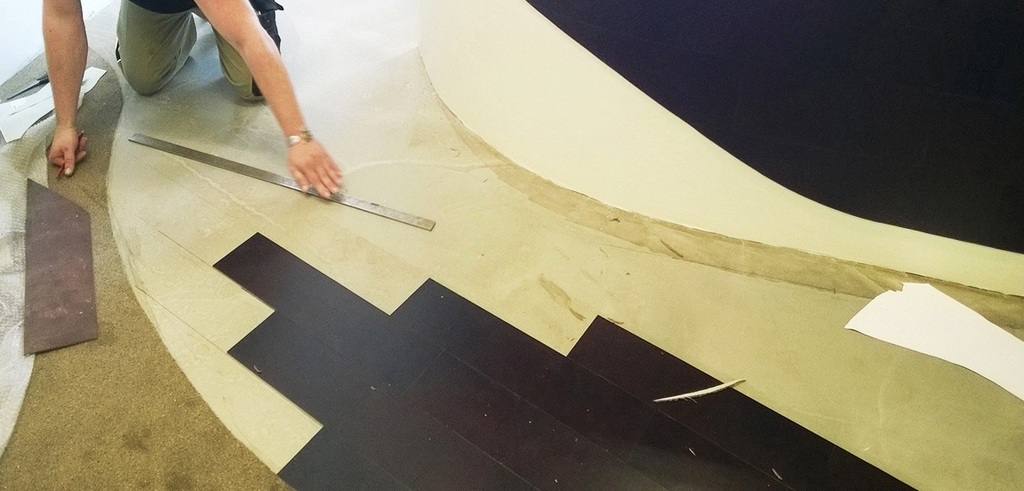 Installer laying a leather floor, with a leather-clad bar counter behind him.