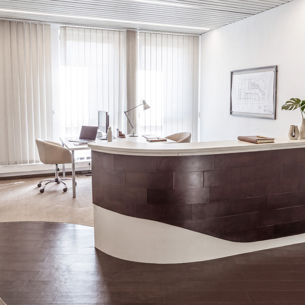 Reception desk paneled in brown and white leather with brown leather flooring in front.